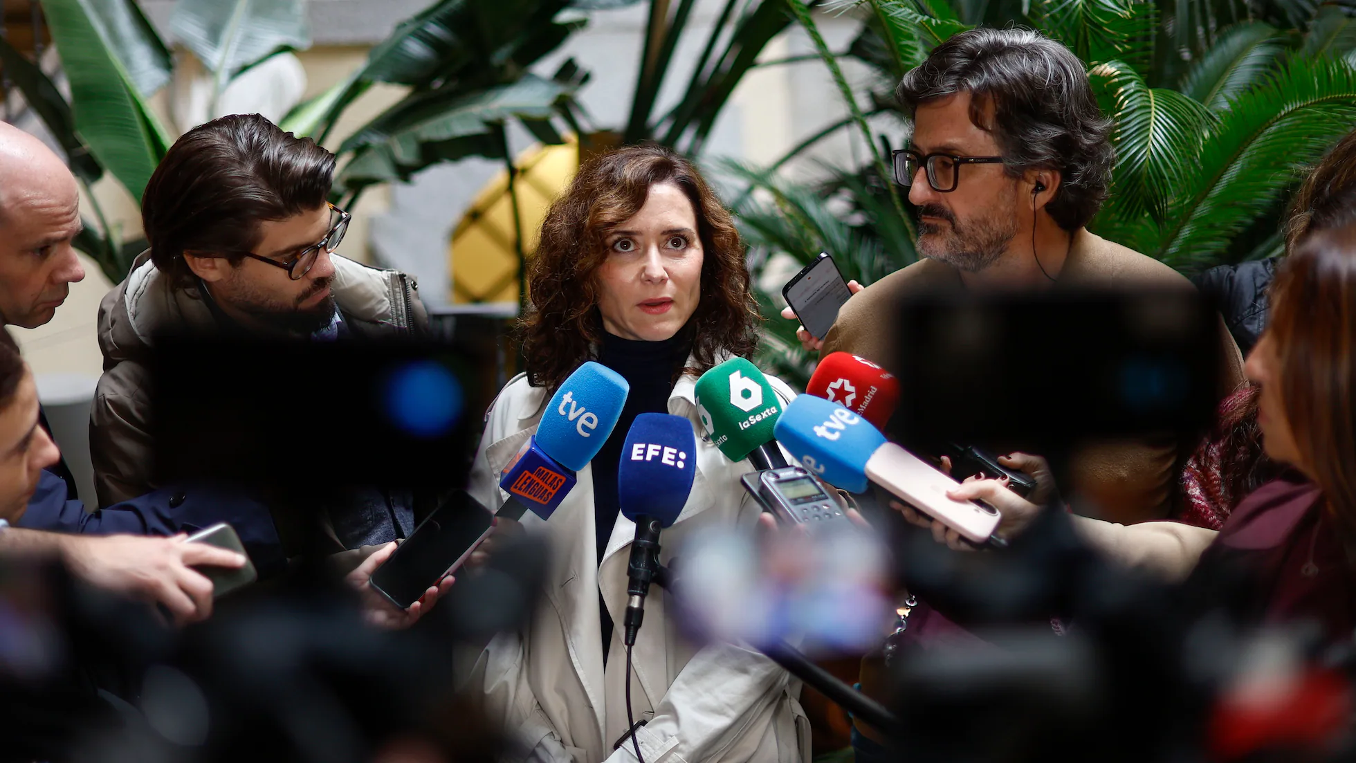 Isabel Díaz Ayuso atendiendo a los medios de comunicación rodeada de micrófonos y periodistas con cámaras en una rueda de prensa en Madrid