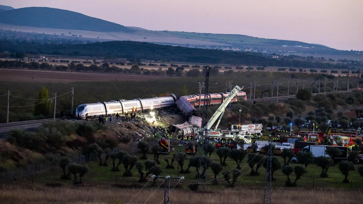 Fotografía editorial de un accidente ferroviario en España con vagones descarrilados en una zona rural y equipos de emergencia trabajando.