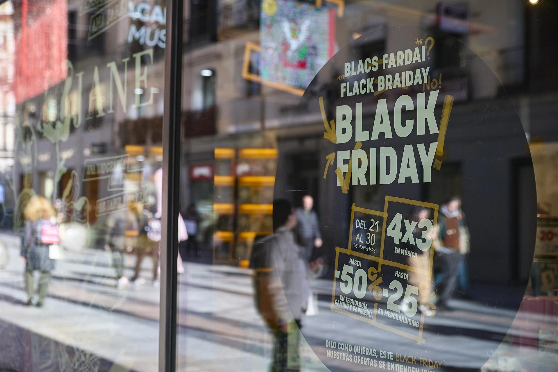 Cartel publicitario de Black Friday en el escaparate de una tienda, reflejando la calle y a los transeúntes.