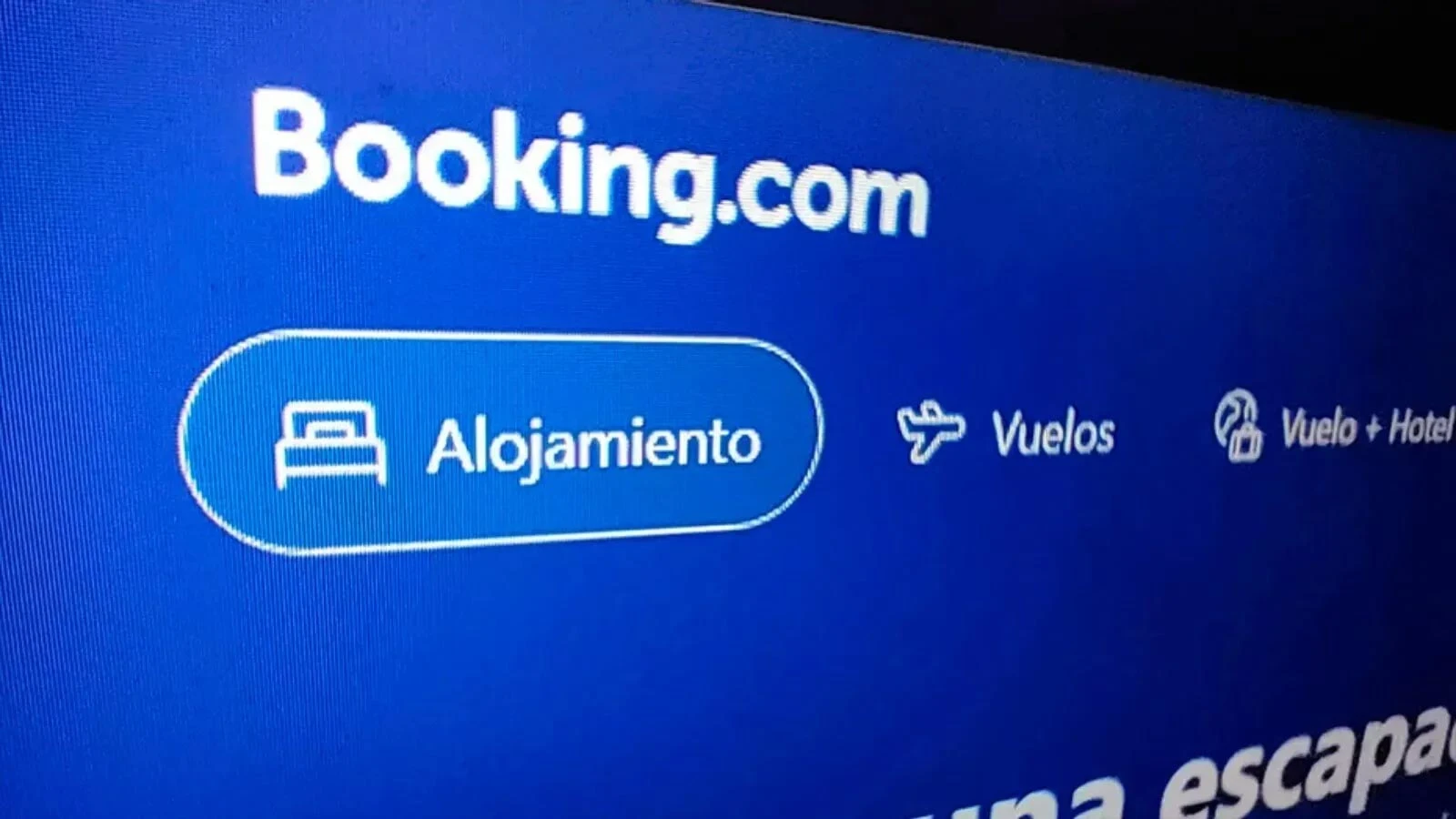 Pantalla que muestra la interfaz de Booking.com con los botones de alojamiento y vuelos en azul