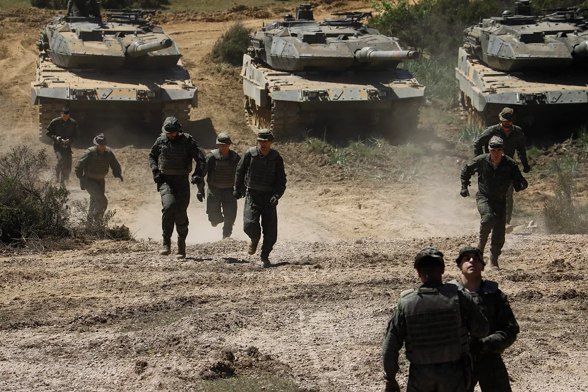 Soldados y tanques Leopard de la Brigada Guzmán el Bueno X realizando maniobras militares en terreno polvoriento.