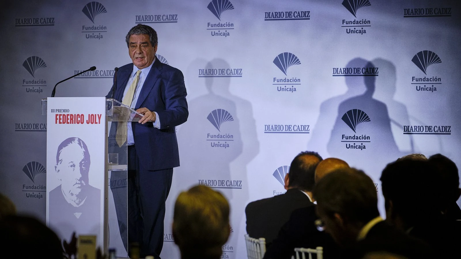 Fotografía editorial de Augusto Delkáder pronunciando un discurso en un atril durante un acto del Diario de Cádiz y la Fundación Unicaja.
