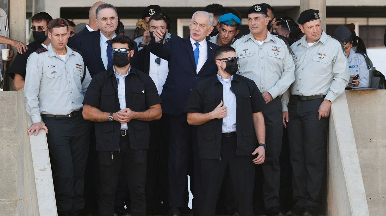 Benjamin Netanyahu señalando con el dedo junto a oficiales militares y guardaespaldas en un acto oficial.