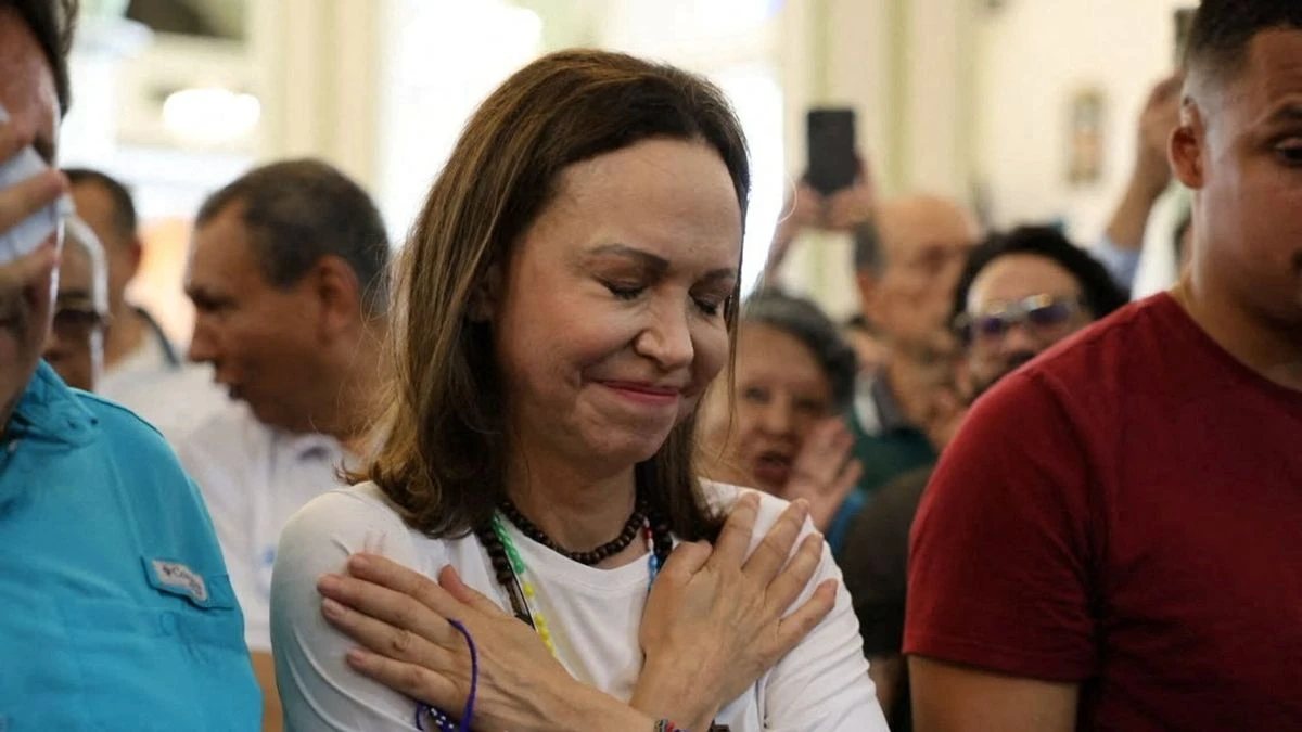 María Corina Machado con los ojos cerrados y las manos cruzadas sobre el pecho en un acto público.