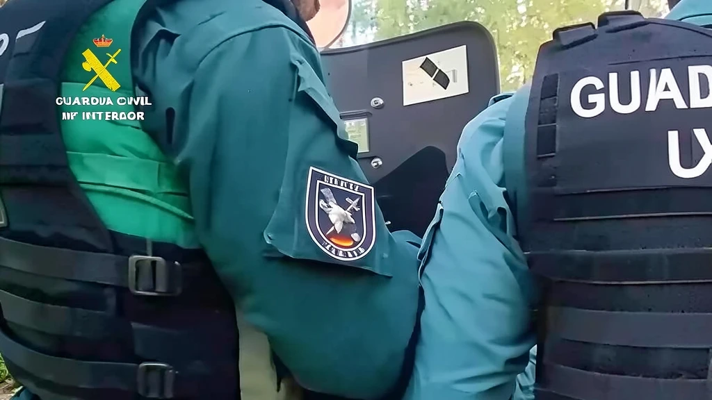 Dos agentes de la Guardia Civil con chalecos tácticos y uniforme verde oscuro durante una intervención policial con escudo antidisturbios.