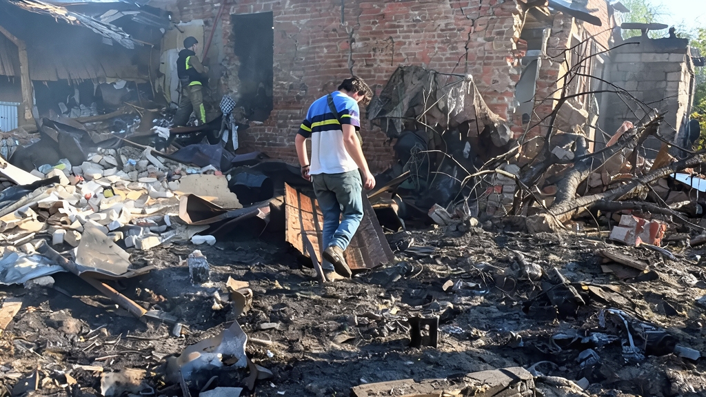 Fotografía periodística de las consecuencias de un ataque en Ucrania, mostrando escombros, una persona inspeccionando los daños y un edificio destruido con ladrillos expuestos.
