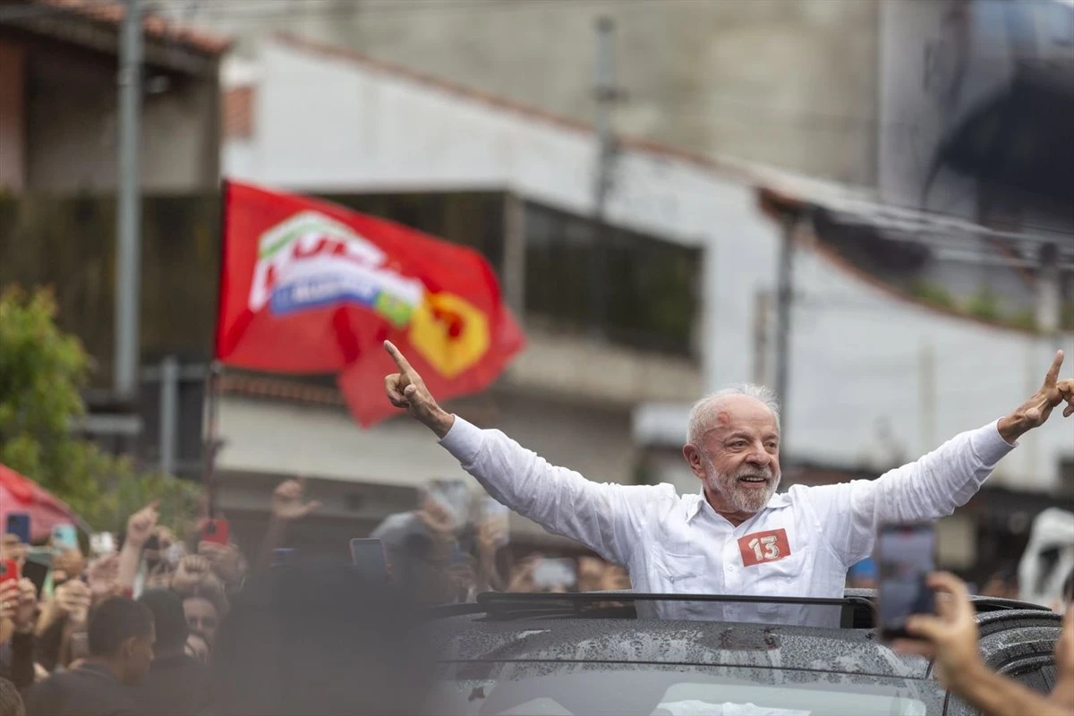 Luiz Inácio Lula da Silva saludando desde el techo de un vehículo rodeado de simpatizantes durante un acto de campaña electoral en Brasil.